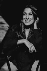 Black and white portrait of a woman sitting on a chair smiling